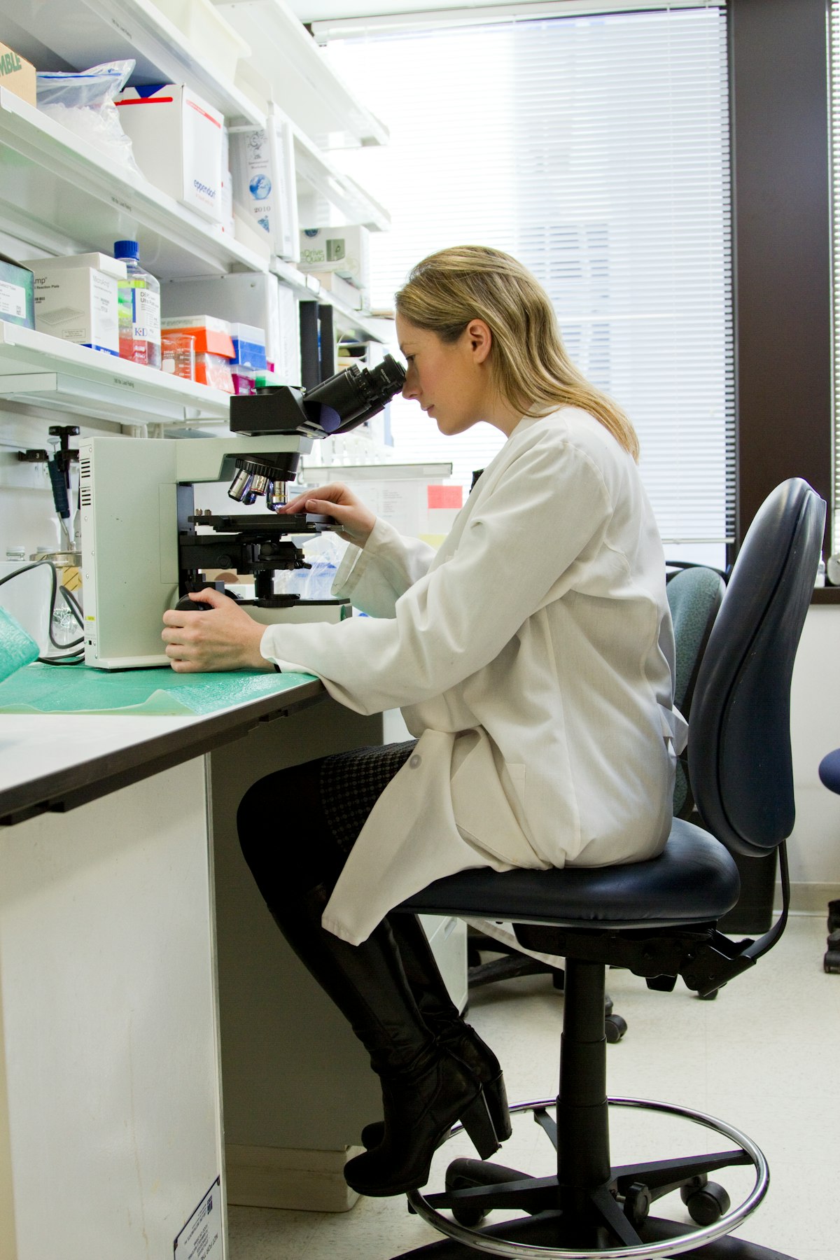A scientist in a lab coat working at a microscope