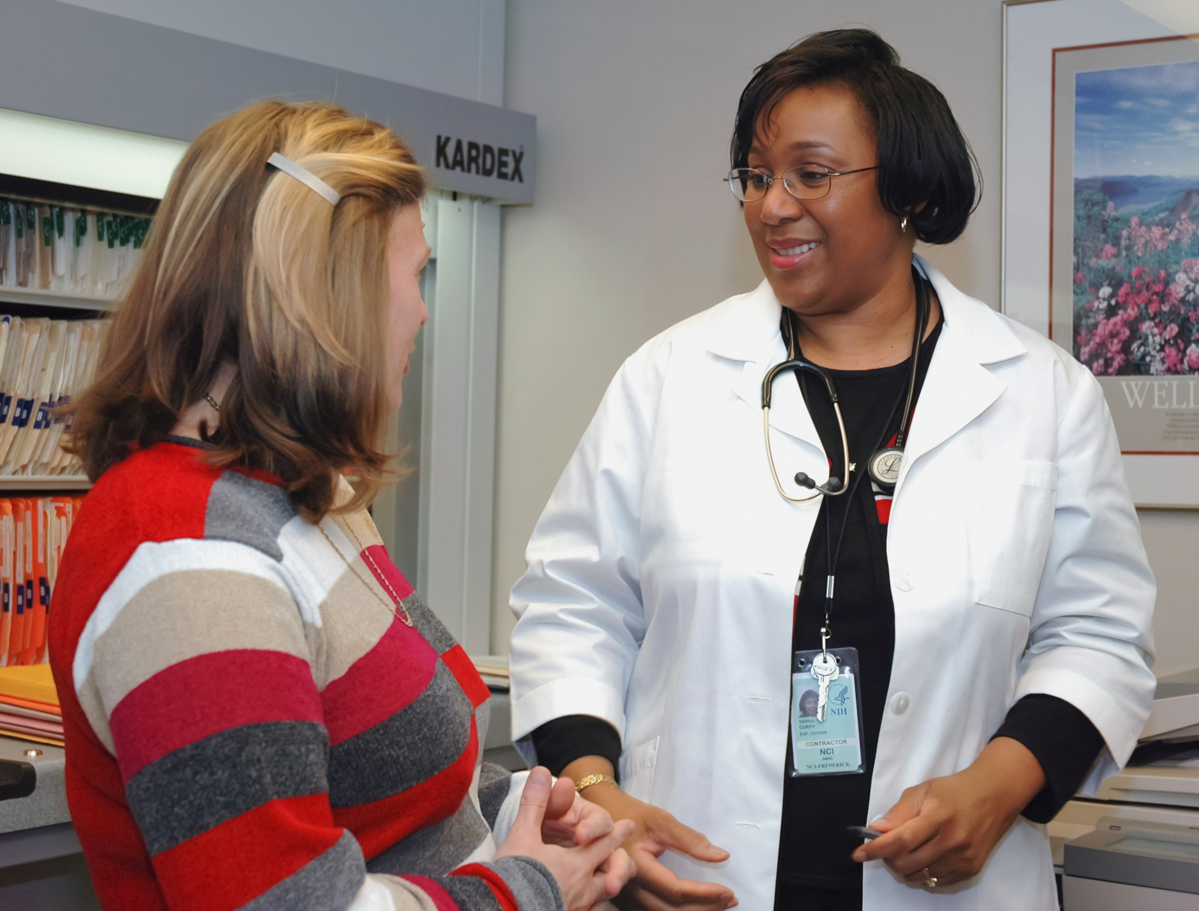A doctor in a white coat talking with a smiling patient in a clinic