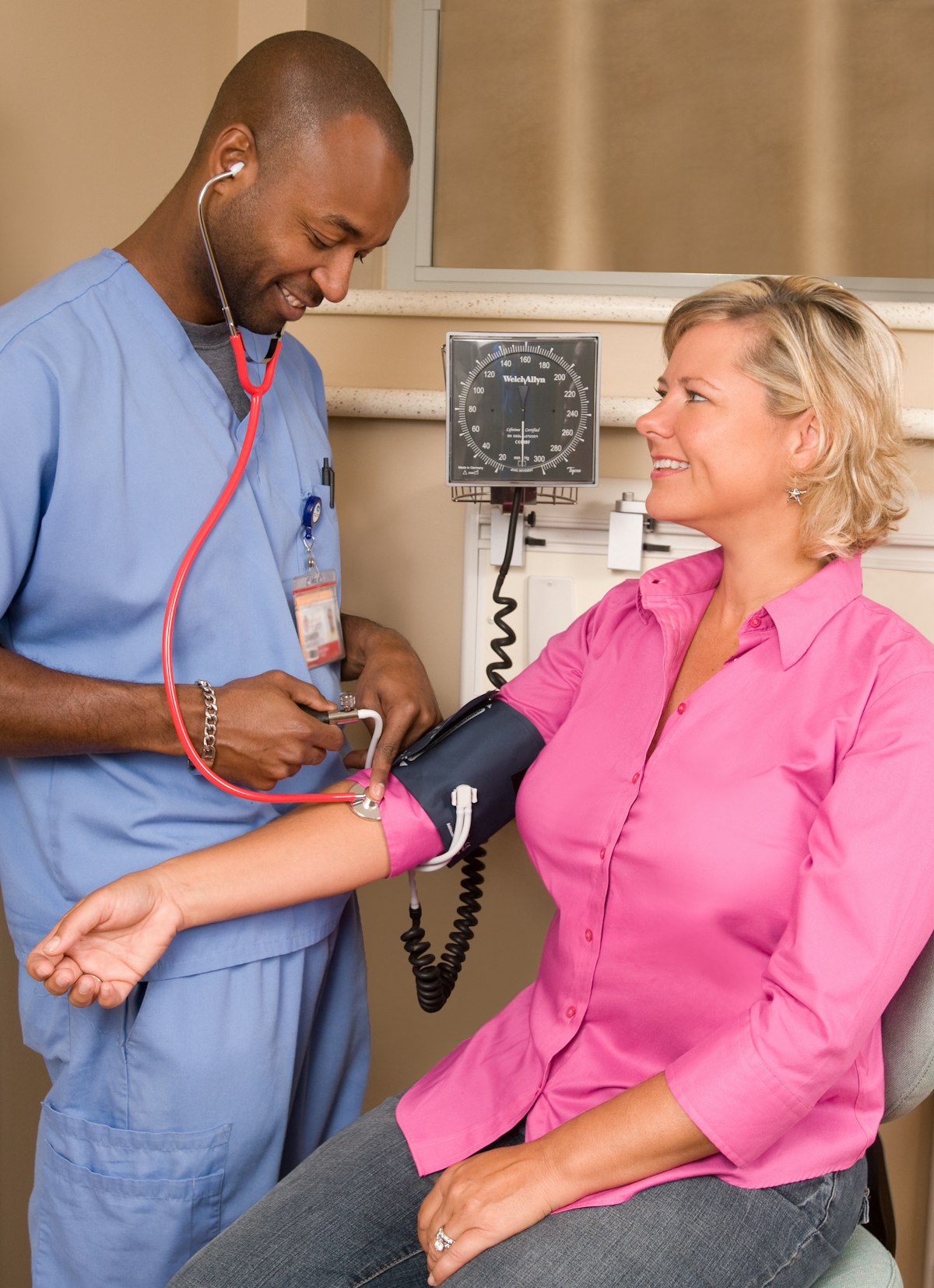 A nurse taking a smiling woman’s blood pressure